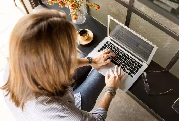 A person using a laptop computer at a table in what appears to be a cafe or office setting